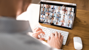 Un individu utilise un ordinateur portable avec un groupe de personnes affiché à l'écran